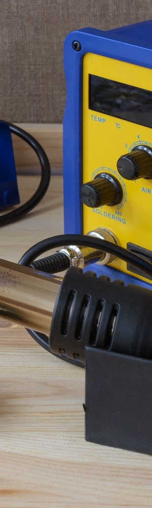 Image of a digital soldering station sitting on a table with soldering iron